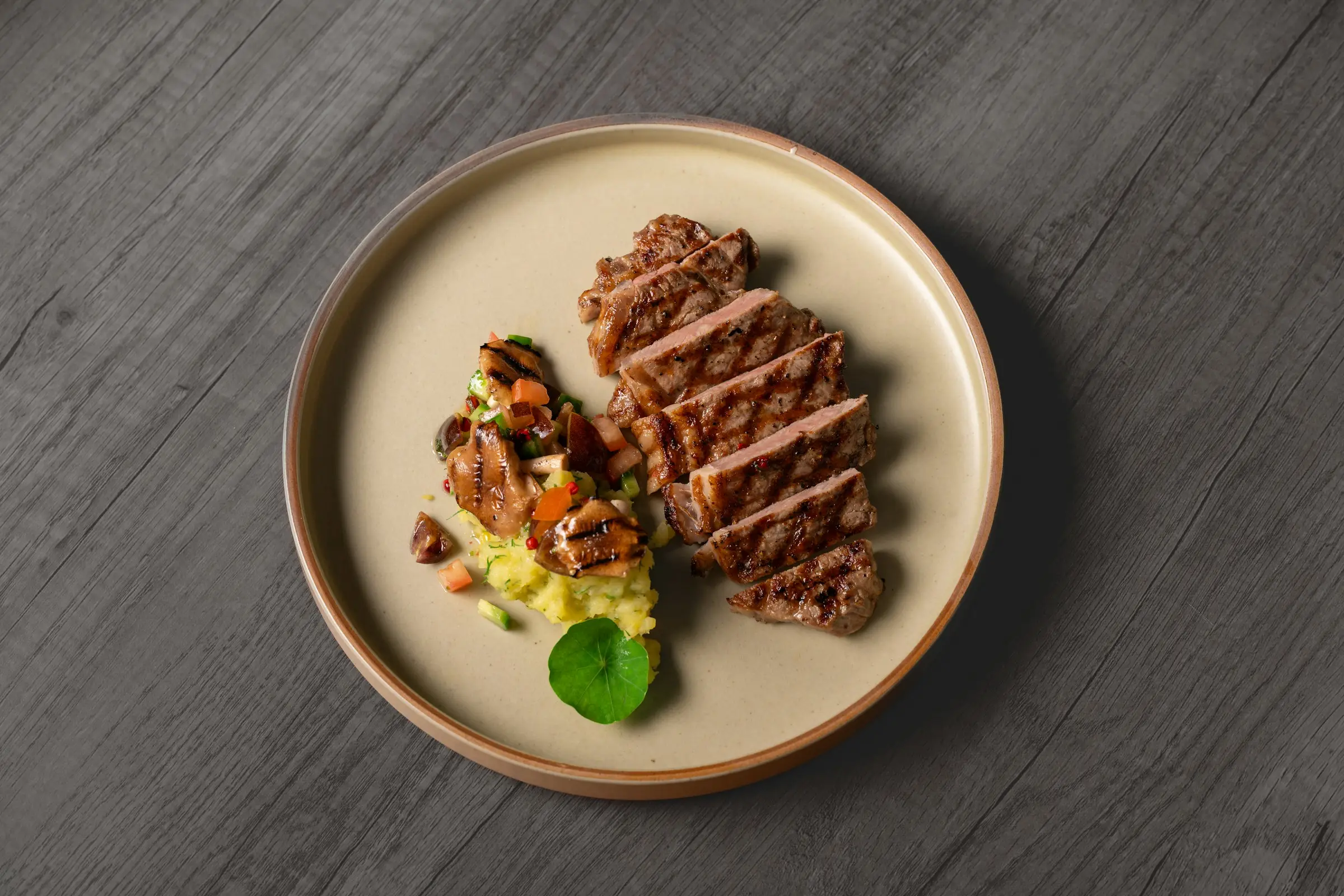 Sliced grilled steak with vegetables on a stoneware plate