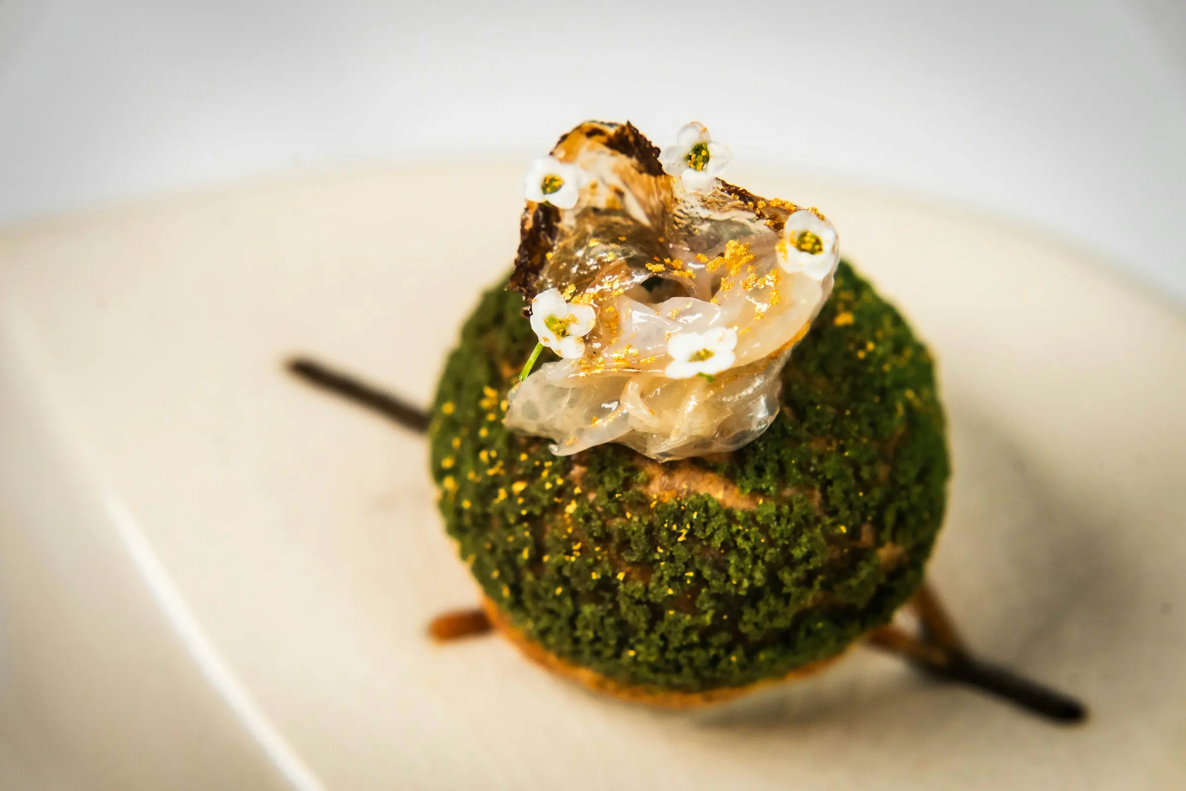 Green dessert dome with gold leaf and white flowers