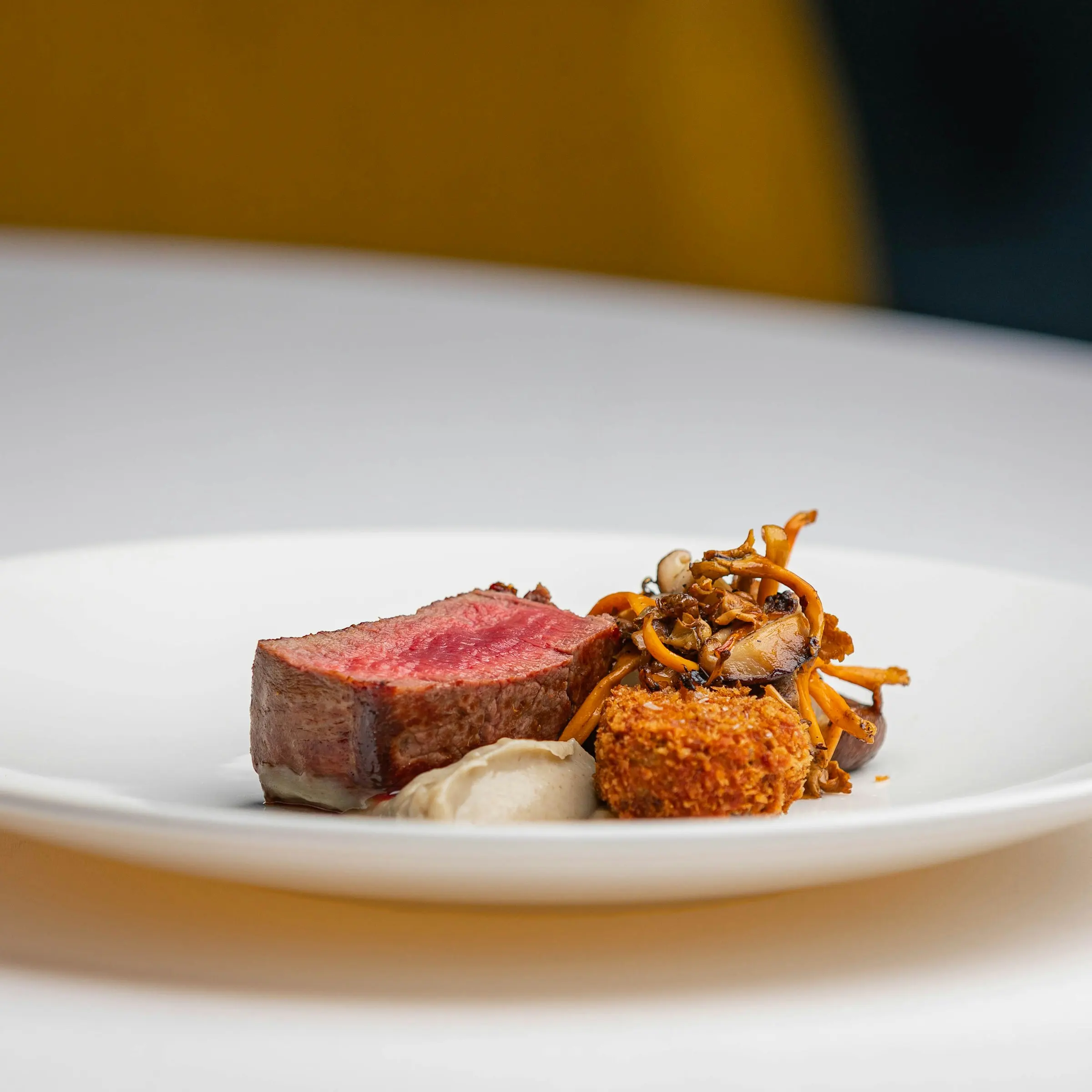 Medium-rare beef fillet with a crisp garnish on a white plate