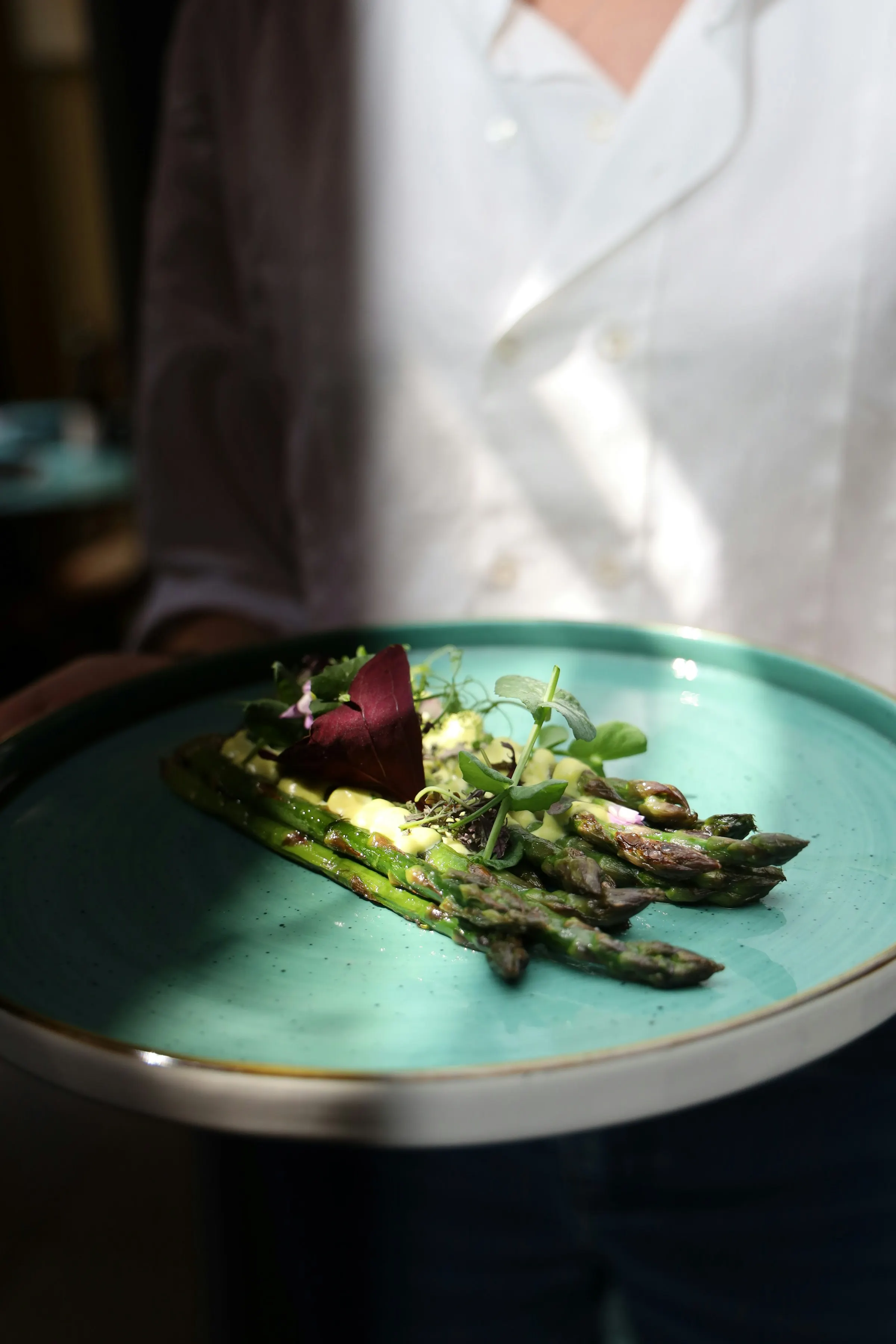 Chef holding a plate of asparagus with beetroot garnish